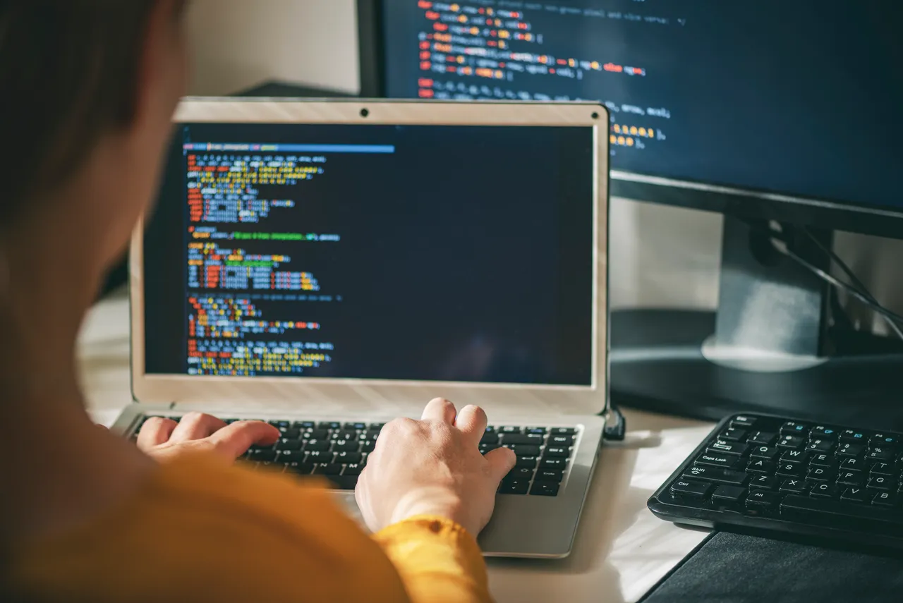 Developer integrating the MyOrbitHealth API on a laptop with code on multiple screens